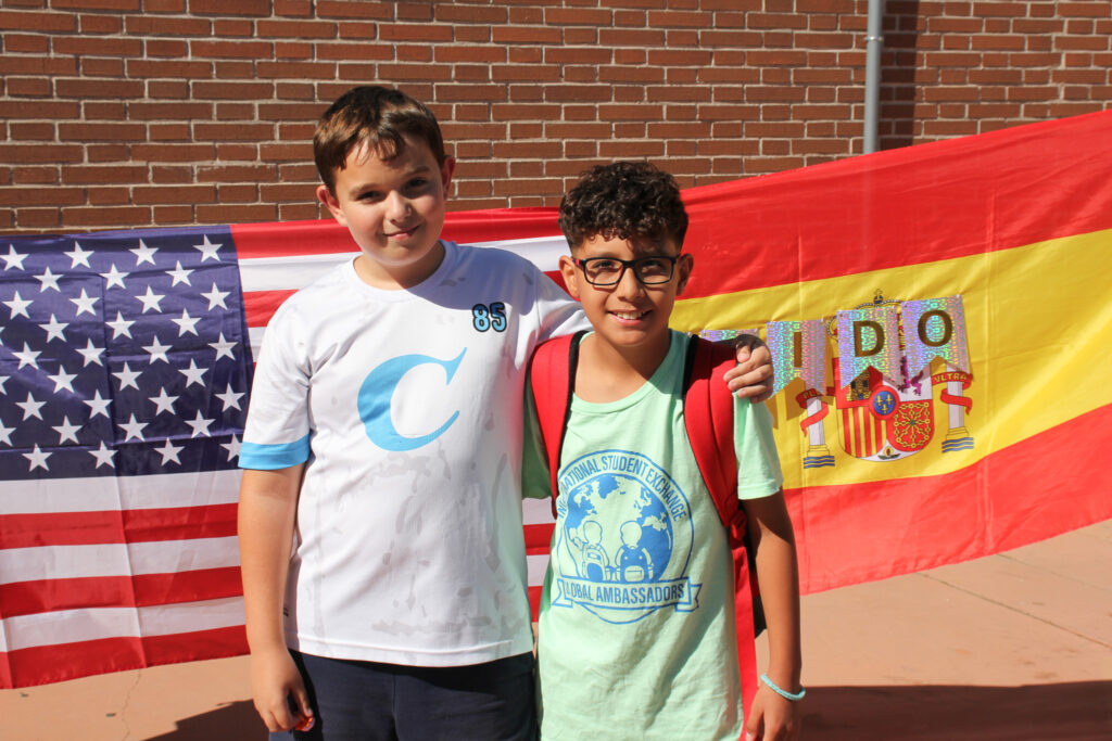 Niño de Estados Unidos junto a niño Español frente a banderas