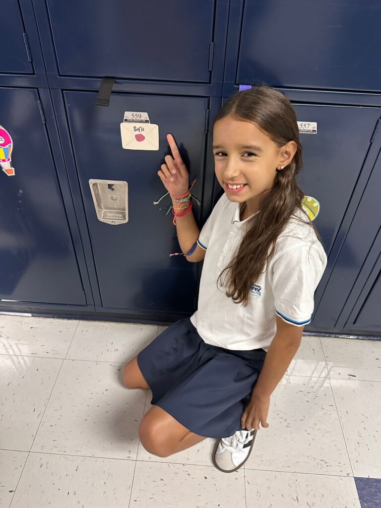 Niña en frente de taquilla en el colegio.