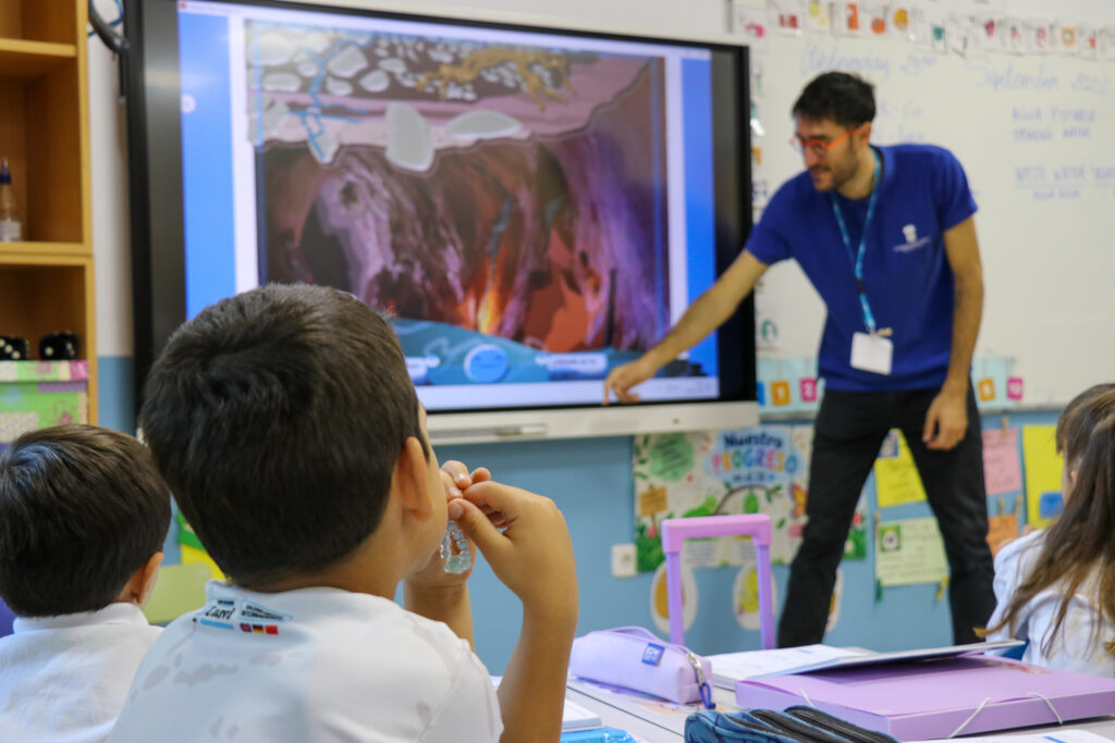 Personal de Canal Educa señala la pantalla mientras un niño lo observa